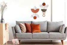 Orange, red and beige pillows on grey comfortable couch in chic living room interior